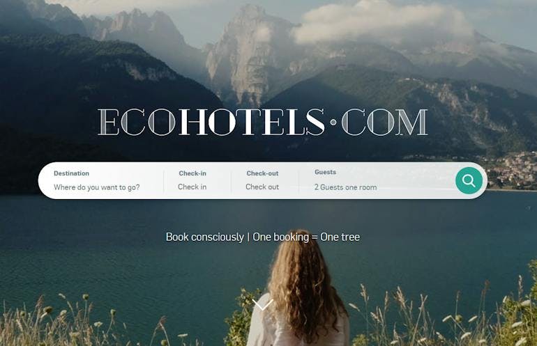 A screenshot of the Ecohotels.com homepage with a search bar showing destinations, dates, and traveler numbers. The search bar is below the ecohotels.com logo text, and it's all overlaid on an image of a lake with mountains in the background and a woman with long hair standing center frame with her back to the camera.