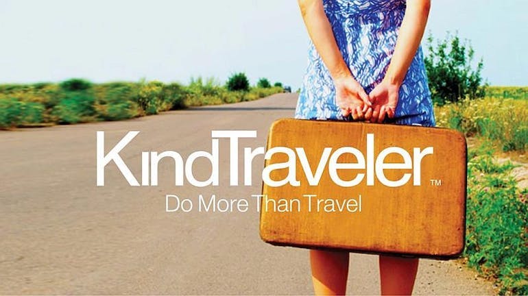 A KindTraveler image showing a white woman holding a brown suitcase standing on a dirt road, with greenery on either sides. White text on screen says "Kind Traveler: do more than travel".