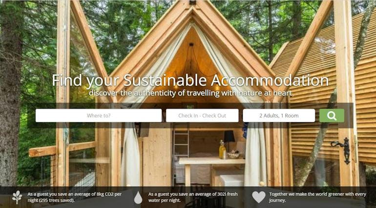 A screenshot of the homepage of Ecobnb showing a search bar where travelers can enter in their destinatino, dates, and traveler numbers to find sustainable accommodation. The background photo is of a wooden house in the forest.